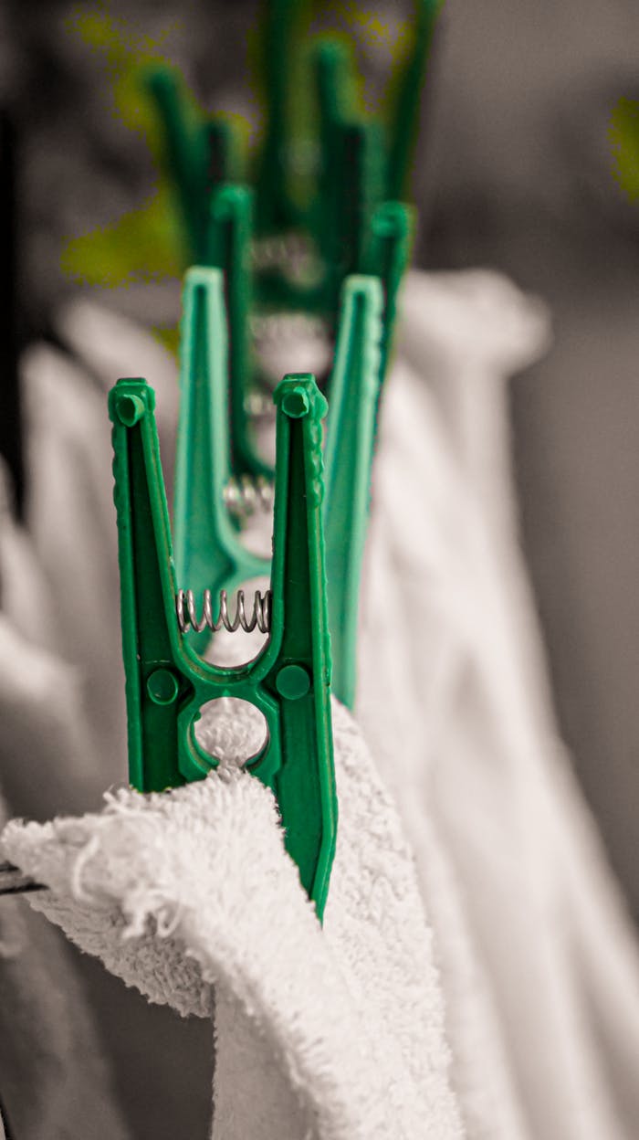 Detailed shot of green clothespins securing white towels on a line.