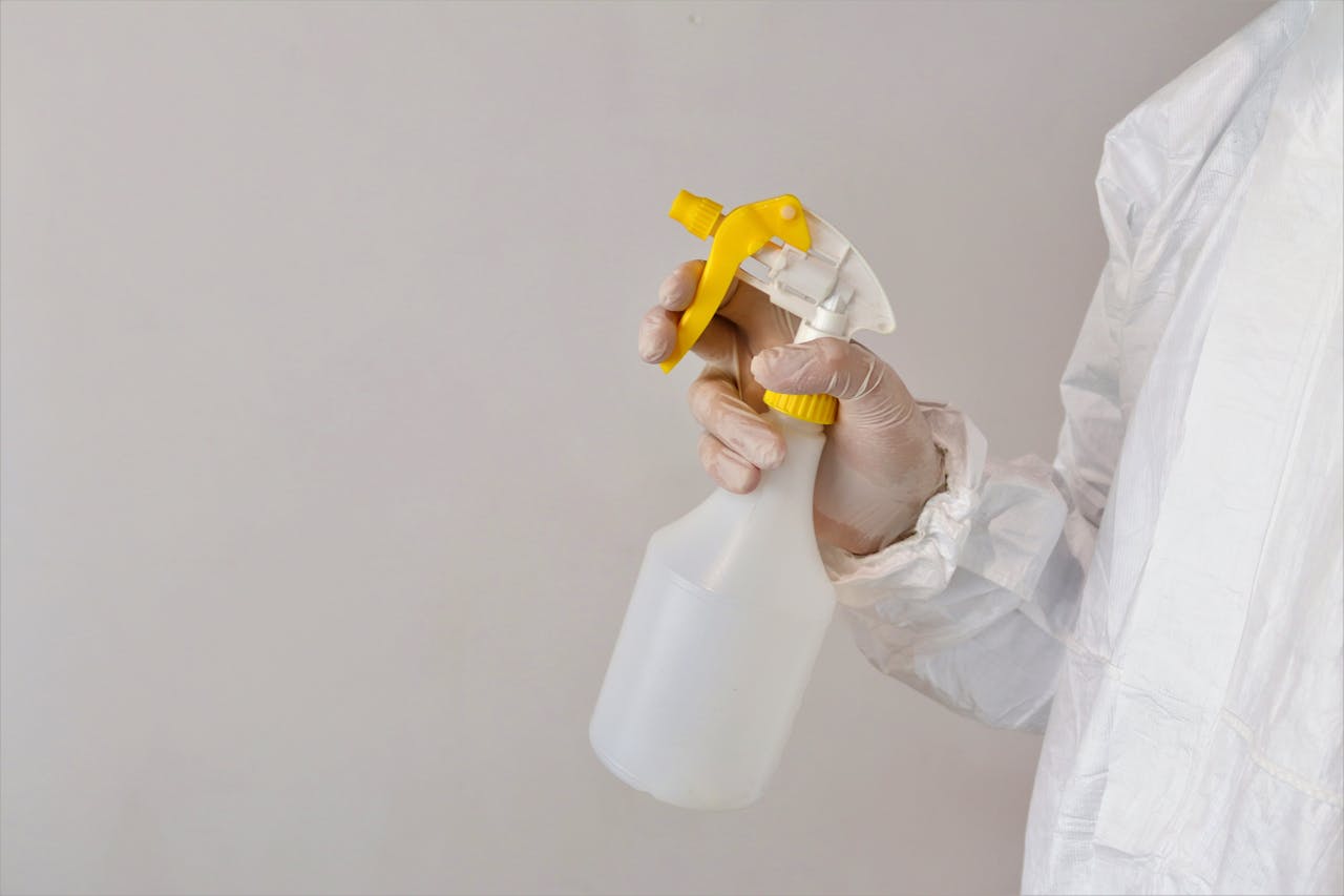 Person in protective gear holding a spray bottle inside a laboratory setting.